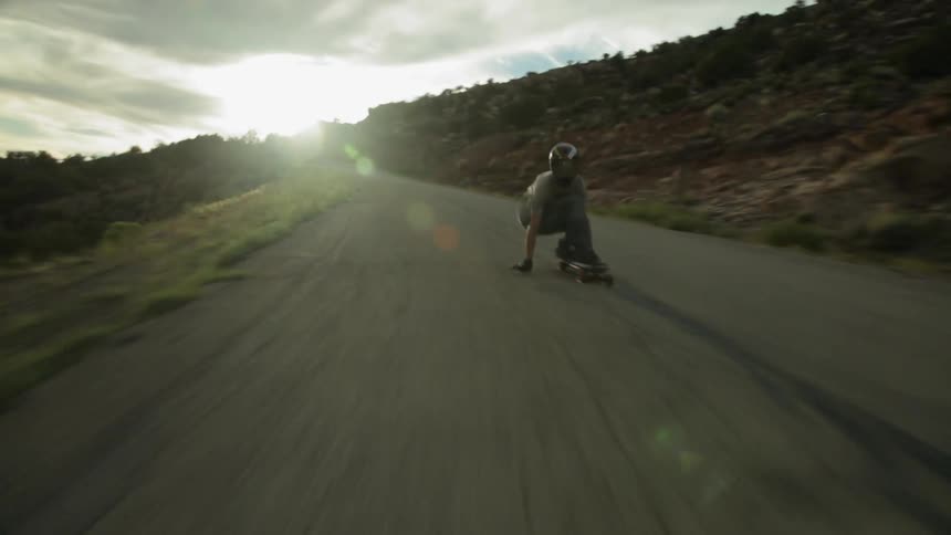 A skateboarder rides down a mountain road at a fast speed