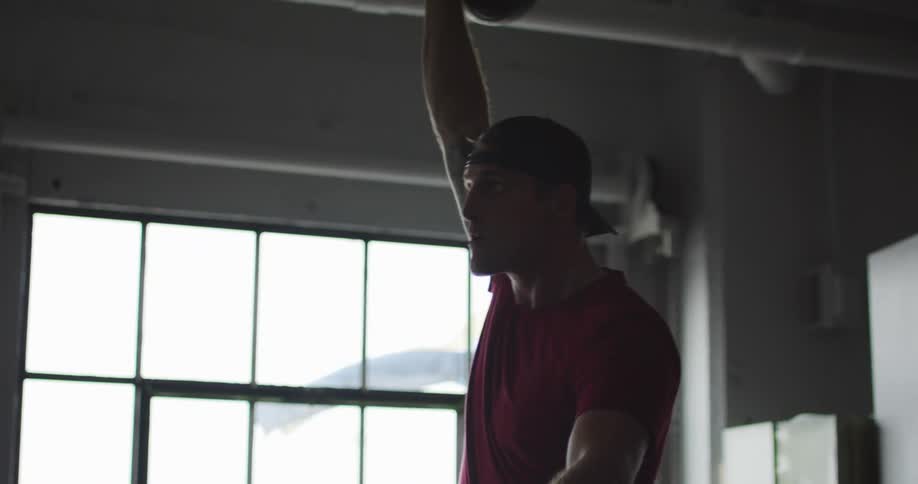 A young man lifts weights in a gym