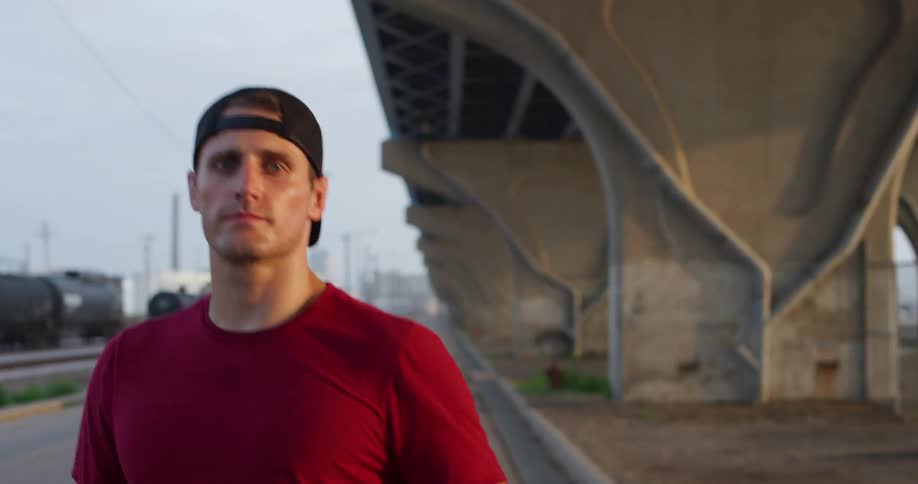 Man starting to run on a street next to a train track and an overpass