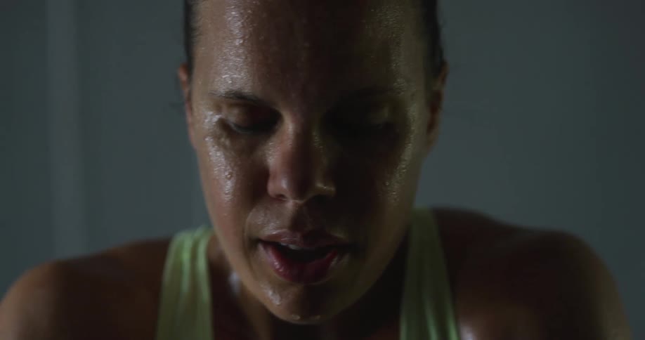 An exhausted woman sweat running down her face takes deep breaths