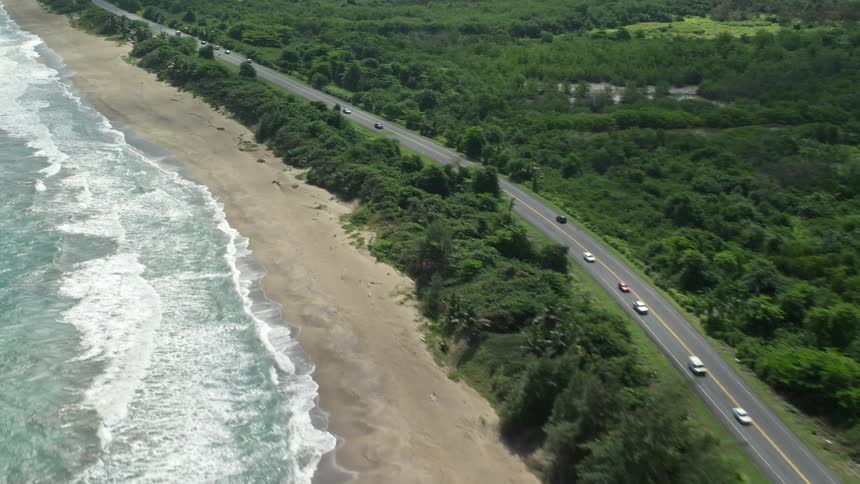 Cars drive along a road next to a coast