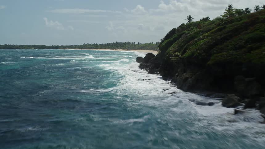 Big waves wash against a beach and rocks
