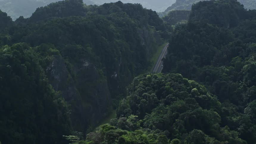Aerial panorama of a highway amidst mountains with forests
