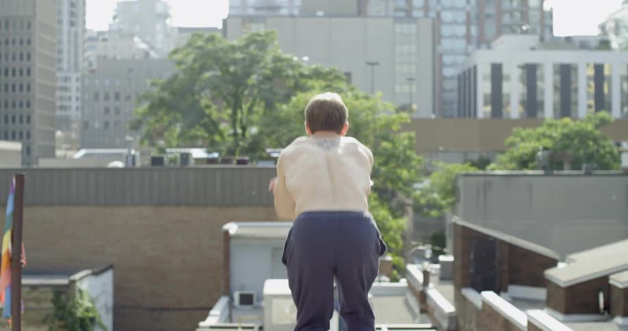 A shirtless man jumps off a building