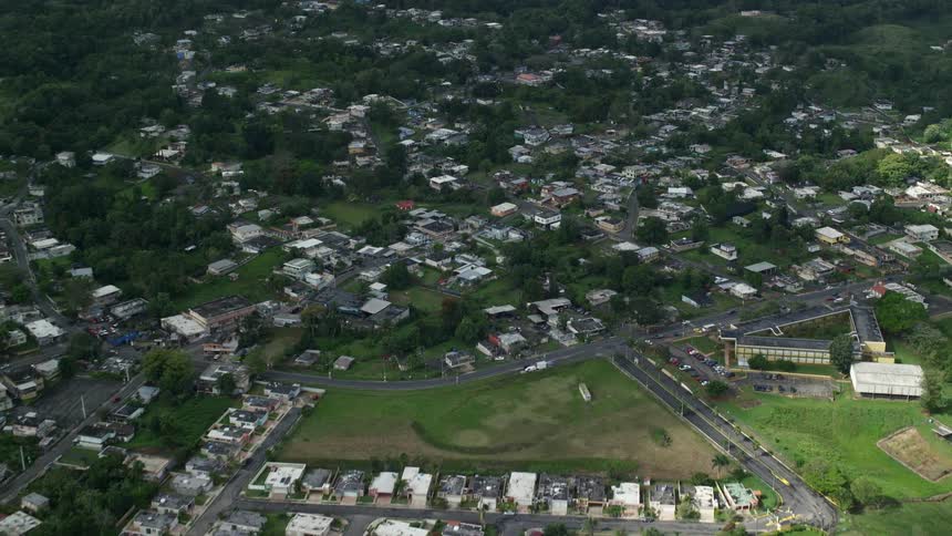 Aerial view of a town in a valley with colorful houses and green hills