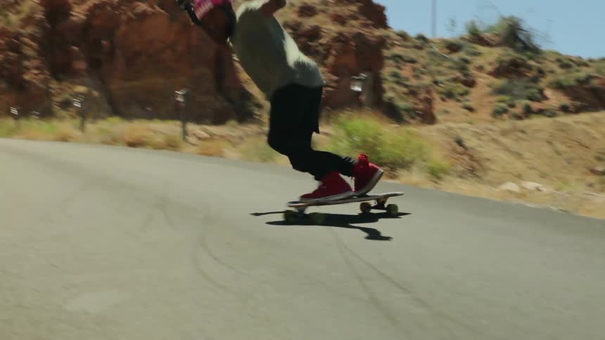 A skateboarder is riding on a street in a desert landscape