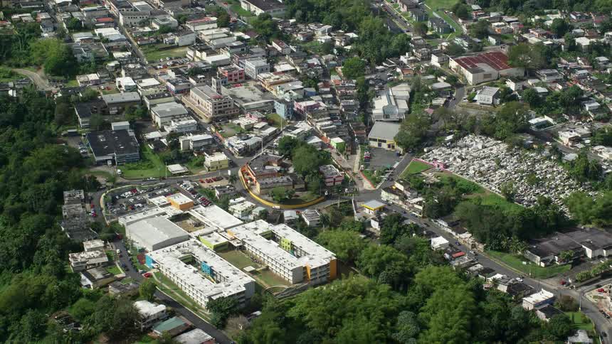 Traffic moves along streets winding through town in forested valley