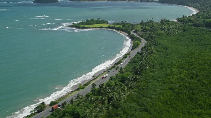 Traffic moves along a coastal road leading to a bay