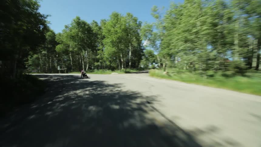A skateboarder rides down a road at a fast speed