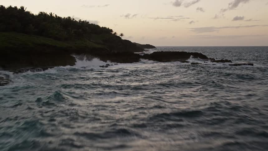 Waves crash against the shore at sunrise