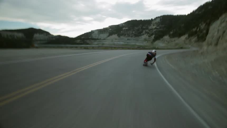 Man riding a skateboard down a mountain highway