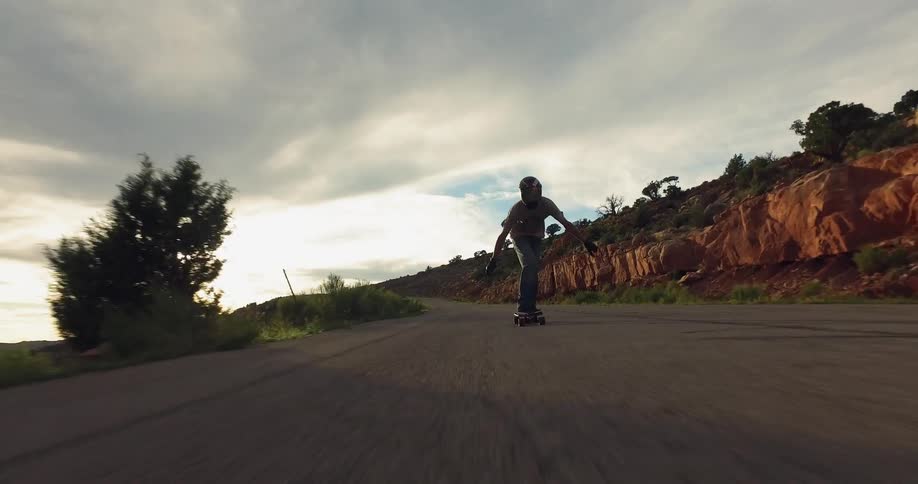 Man riding a skateboard down a mountain highway