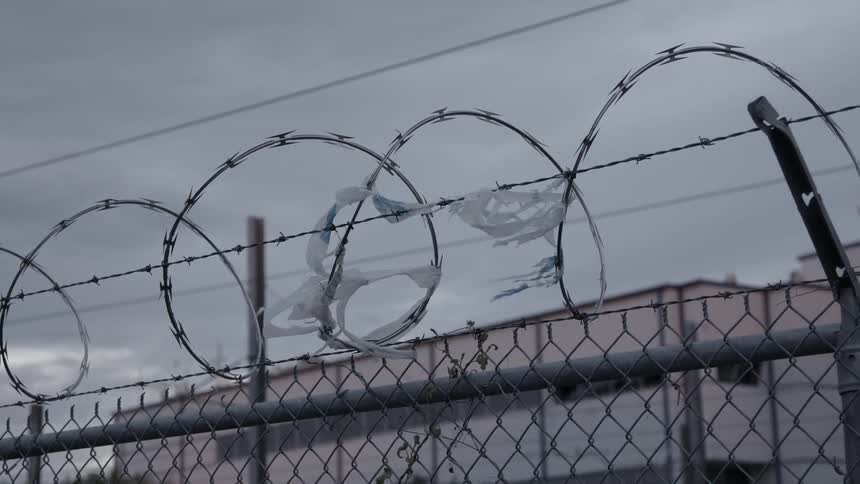 Tattered trash breezes in the wind attached to barbwire