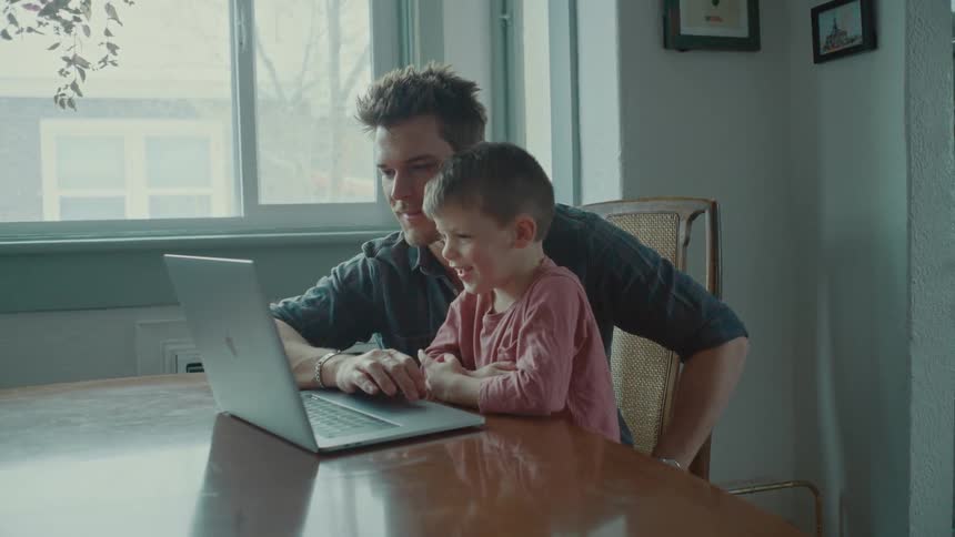 A father shows his son his laptop