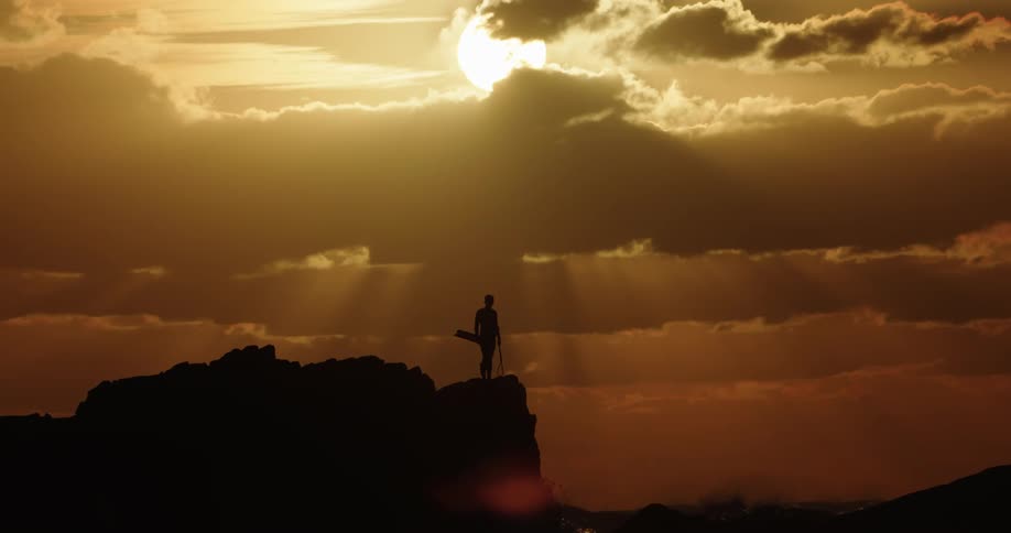 A man stands on rocks next to the ocean