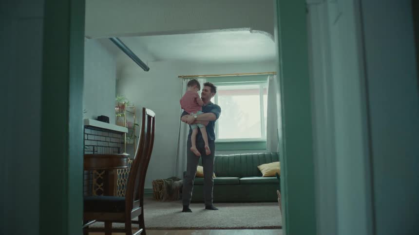 A father picks up his son in a living room