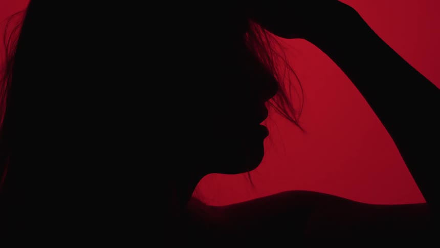 A woman strikes a pose in front of a red background