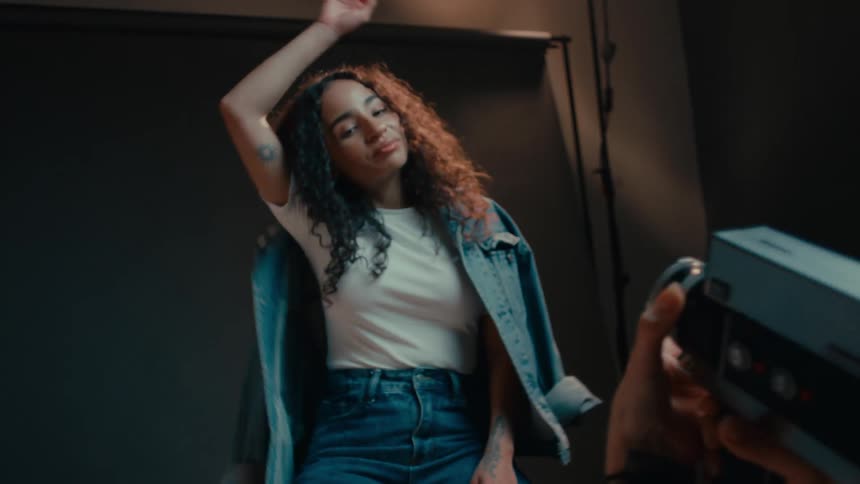 A black woman models for another woman holding a camera