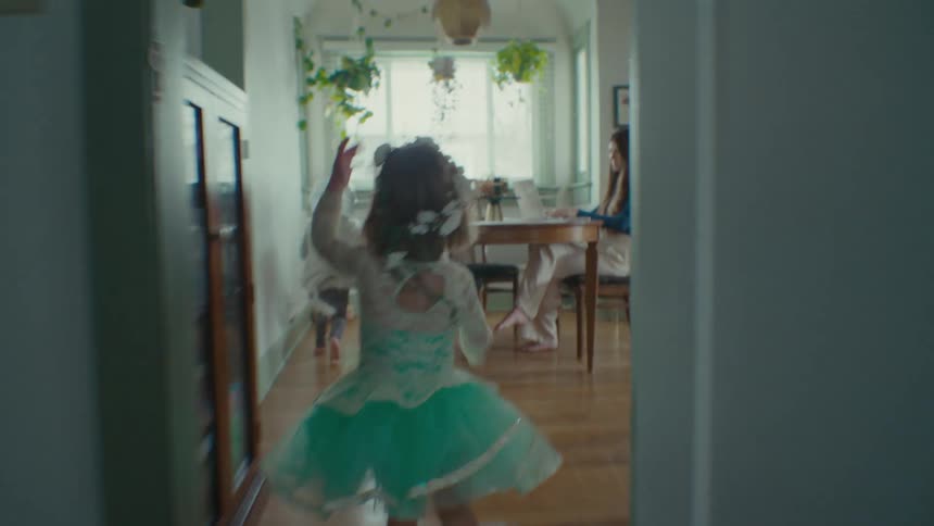 Children running in the room with their mother working on a laptop at the table