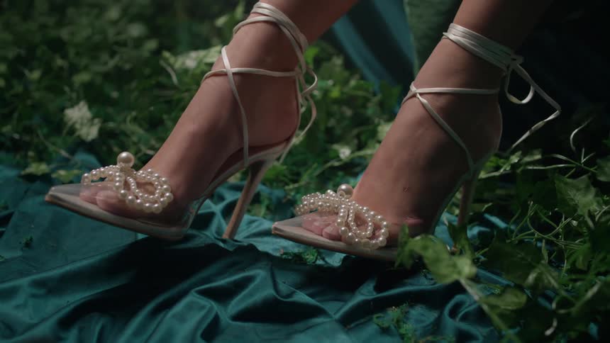 Closeup of a womans feet wearing high heels with pearls