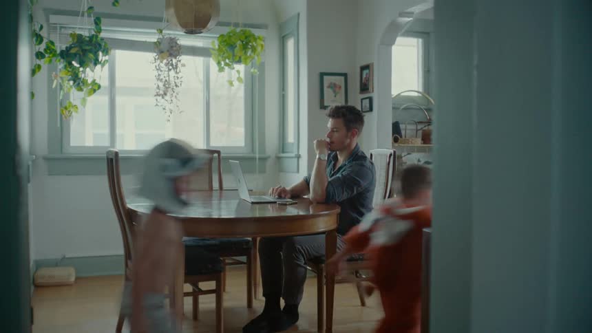 Two boys play as a man answers his phone
