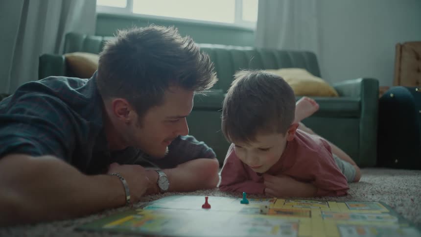 Father and son playing a board game over the rug in the living room