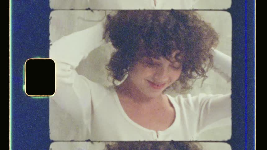 A woman primps her hair while smiling