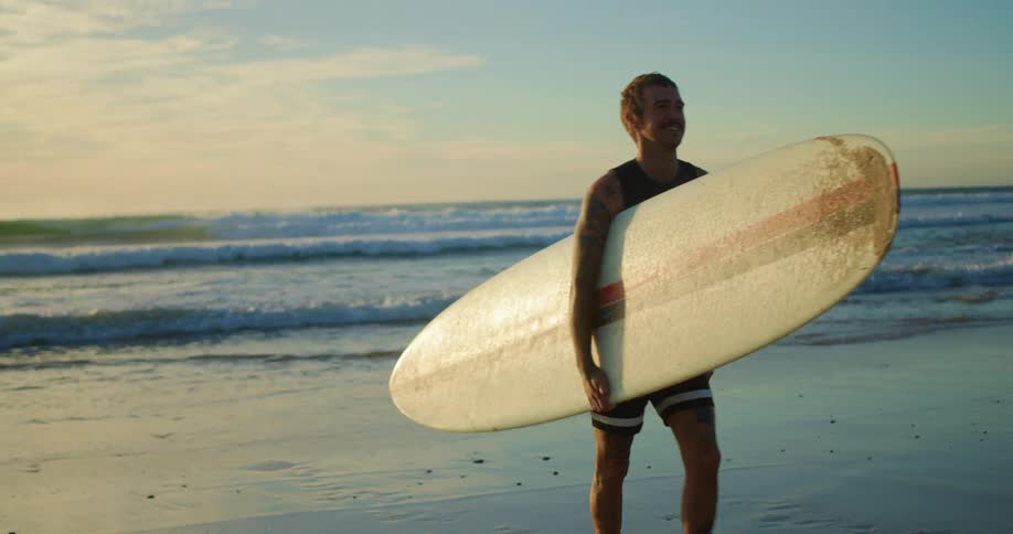A man walks on the beach with his surfboard