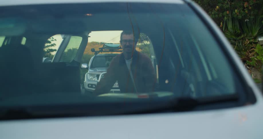 A man removes his surfboard from his car