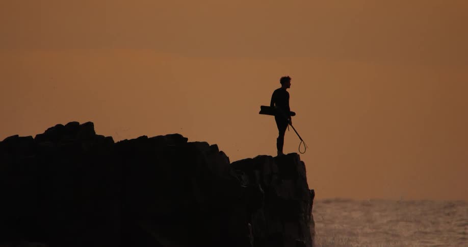 A man stands on a cliff near the ocean