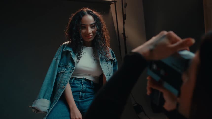 A black woman models clothing and is filmed