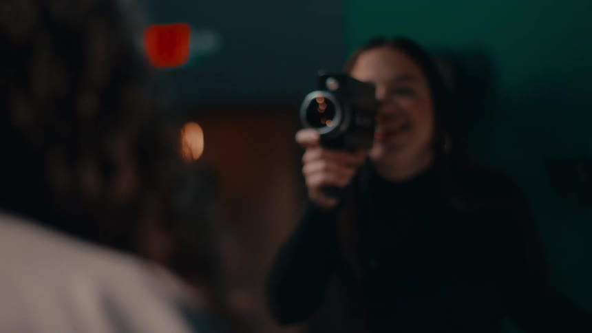 A woman films her friend with a camera