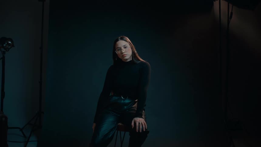 Young model sitting on a stool modeling for the camera