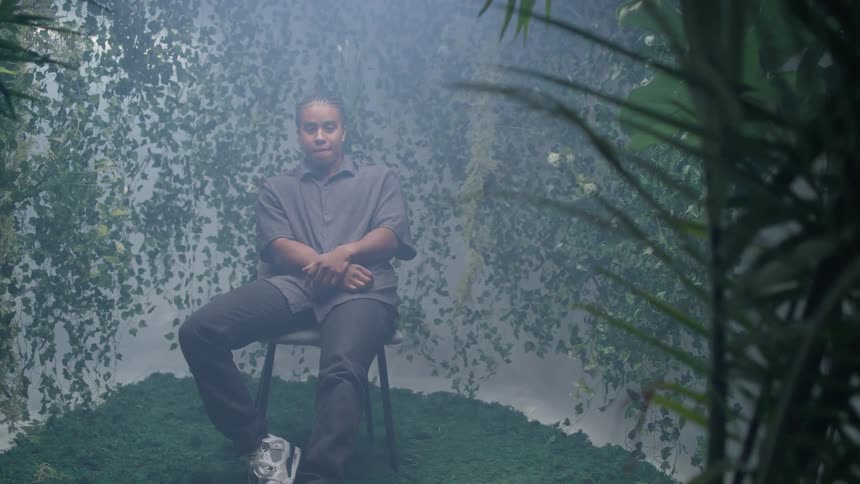 A black model sits on a chair