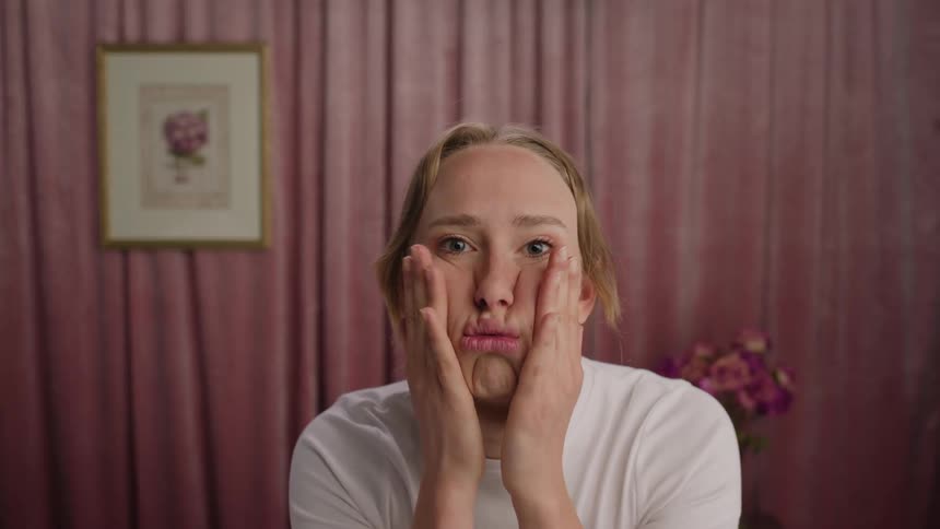 A woman is rubbing her face