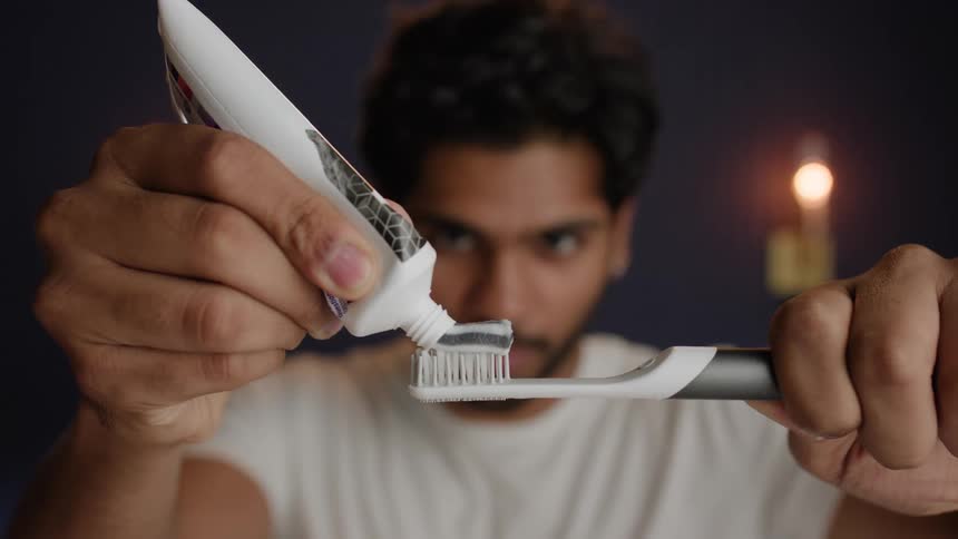 A man puts toothpaste on his toothbrush