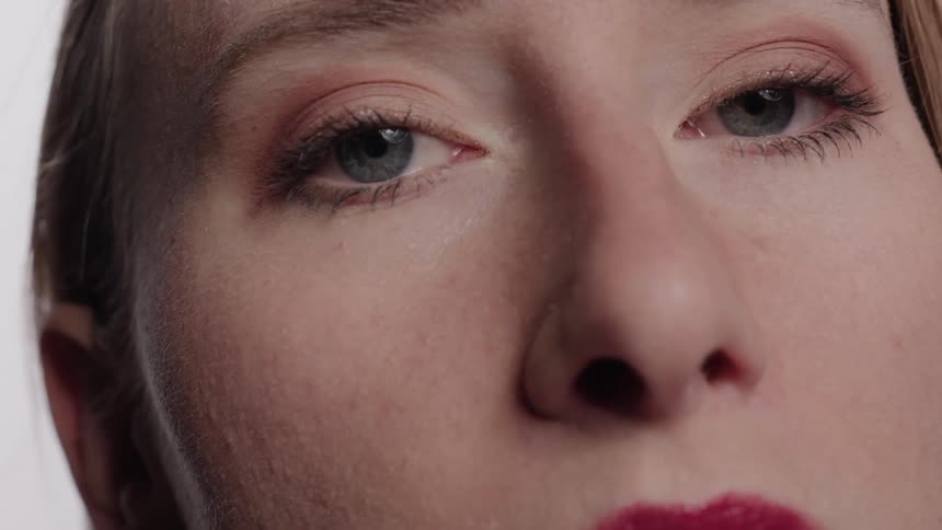 Closeup on the face of a blonde woman with pink lipstick and makeup