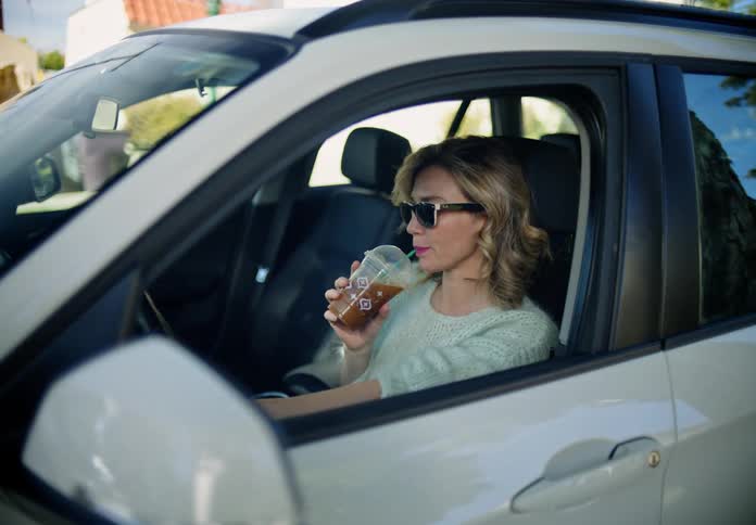 A woman takes a drink while driving