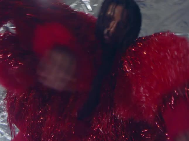 Two models wearing red metallic outfits pose against silver background