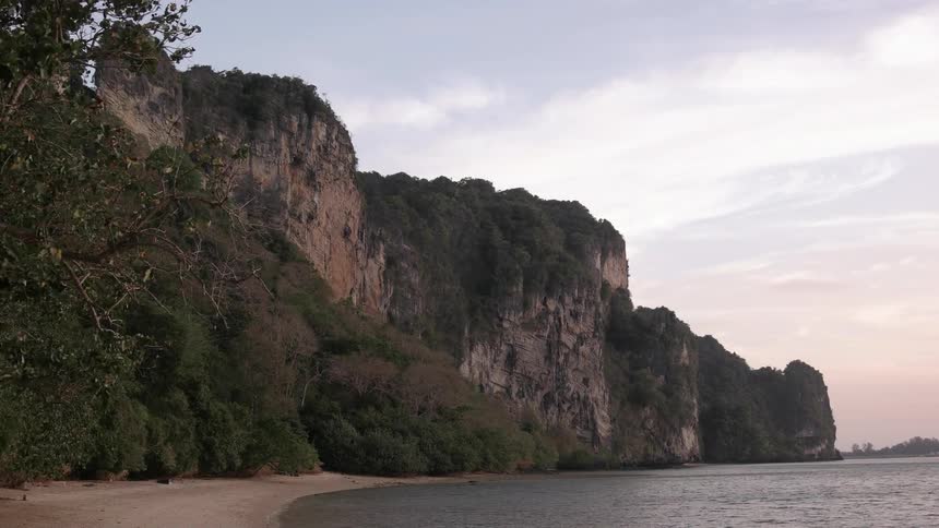 Gentle waves rolling into a beach surrounded by rock cliffs