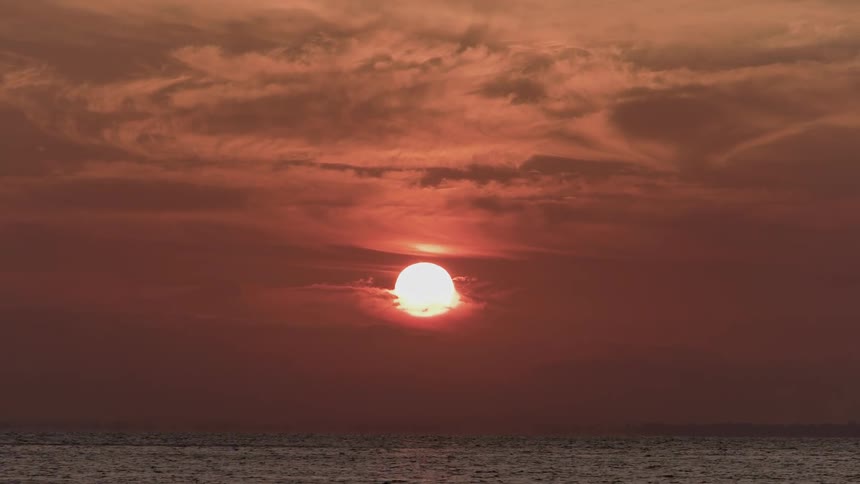 A setting sun glows pink over an ocean
