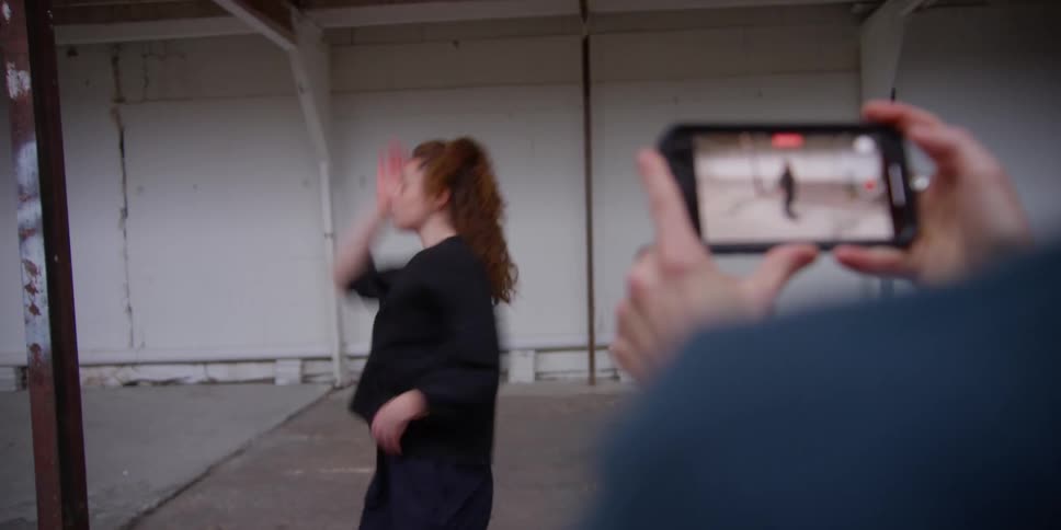 Person uses smartphone to take video of female dancer dancing in studio