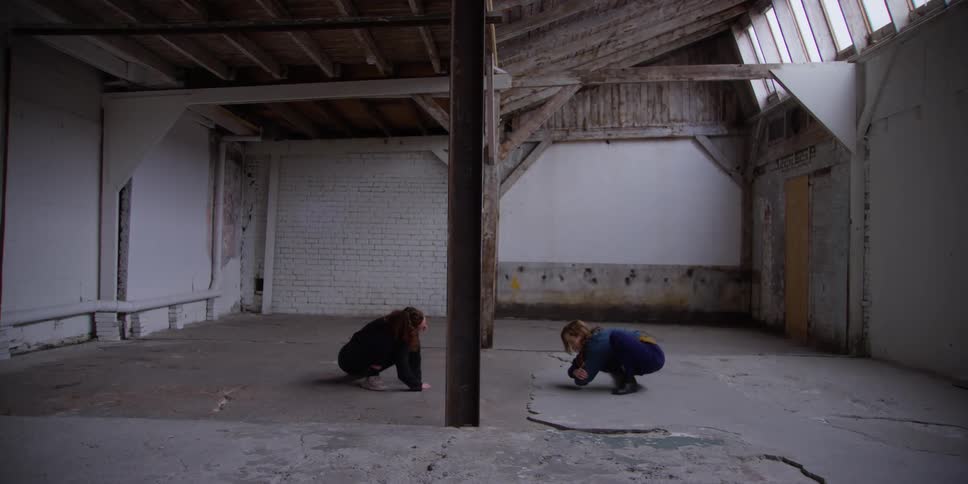 Two females stretching their bodies while in squat positions at daytime