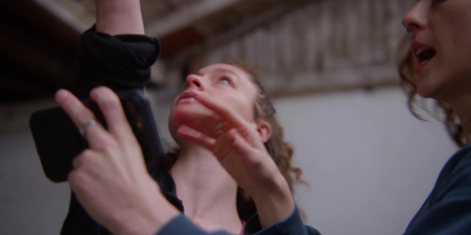Woman teaching a dancer how to move using a video on her smartphone