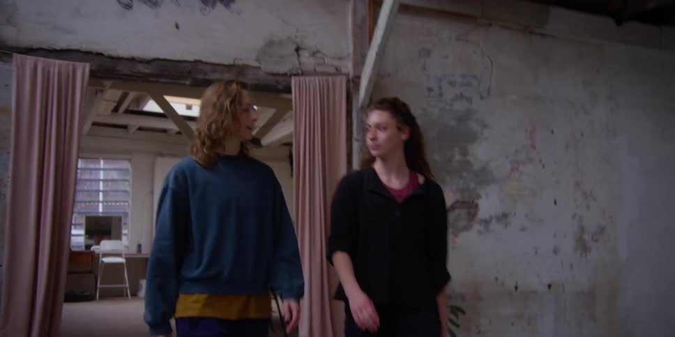 Two females talking while walking through a door at midday