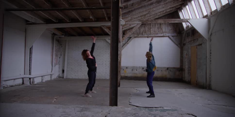Two women warming up their bodies with some exercises in a shed