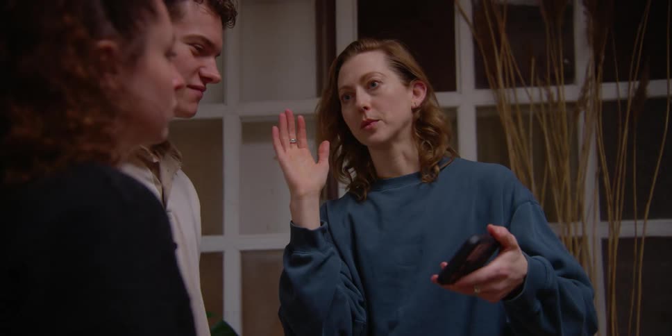 Three people talk while looking at a cell phone