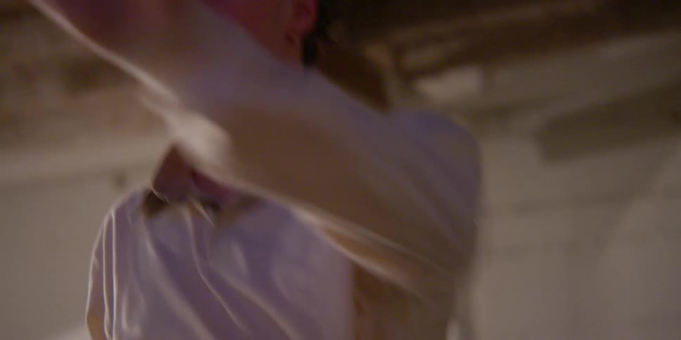 Man wearing a white shirt dances in a room