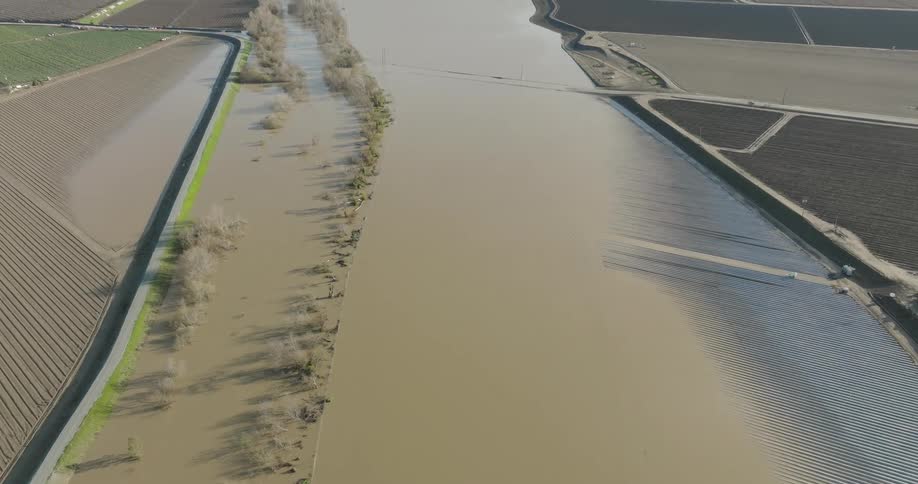 A flooded agricultural area with water overflowing into adjacent fields