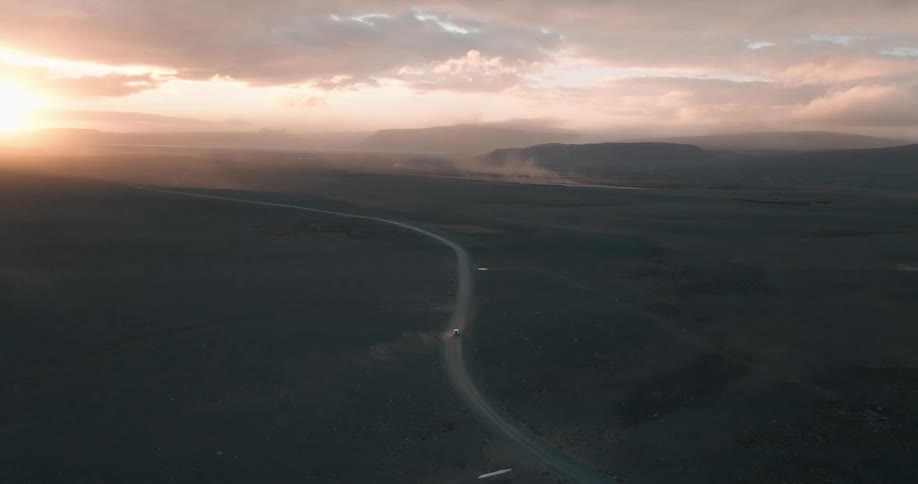 Aerial of a moving vehicle on a sandy road at sunset